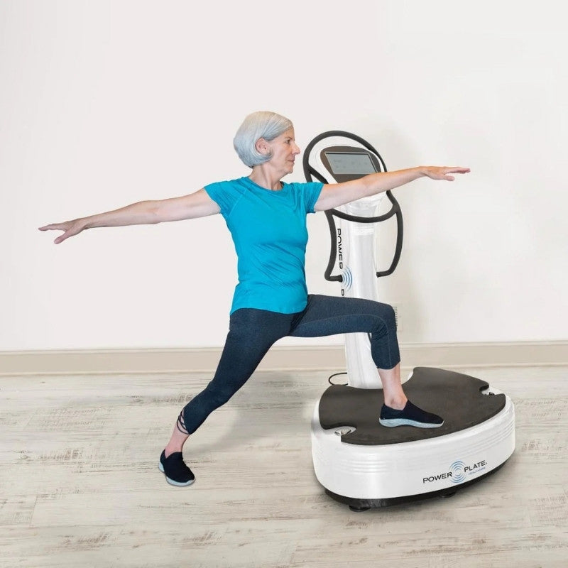 Person using a Power Plate machine for exercise on a wooden floor.