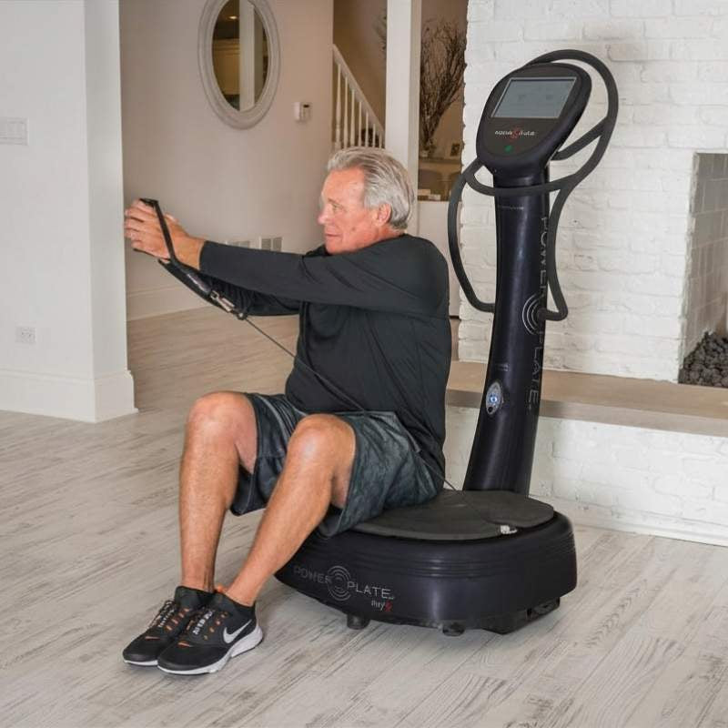 Man using a vibration plate machine in a home setting