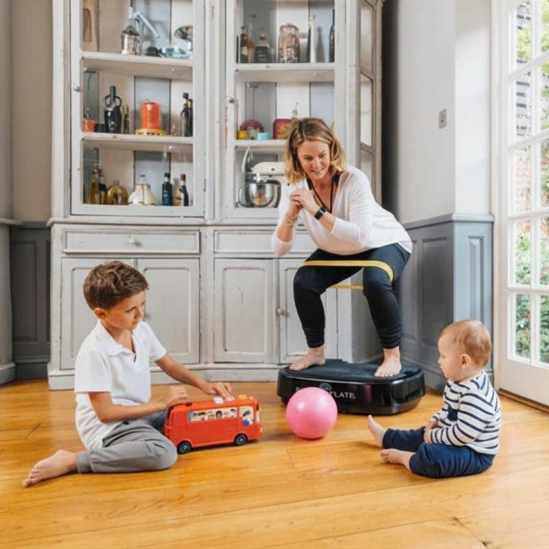 Woman exercising on a step machine with two children playing in a kitchen.