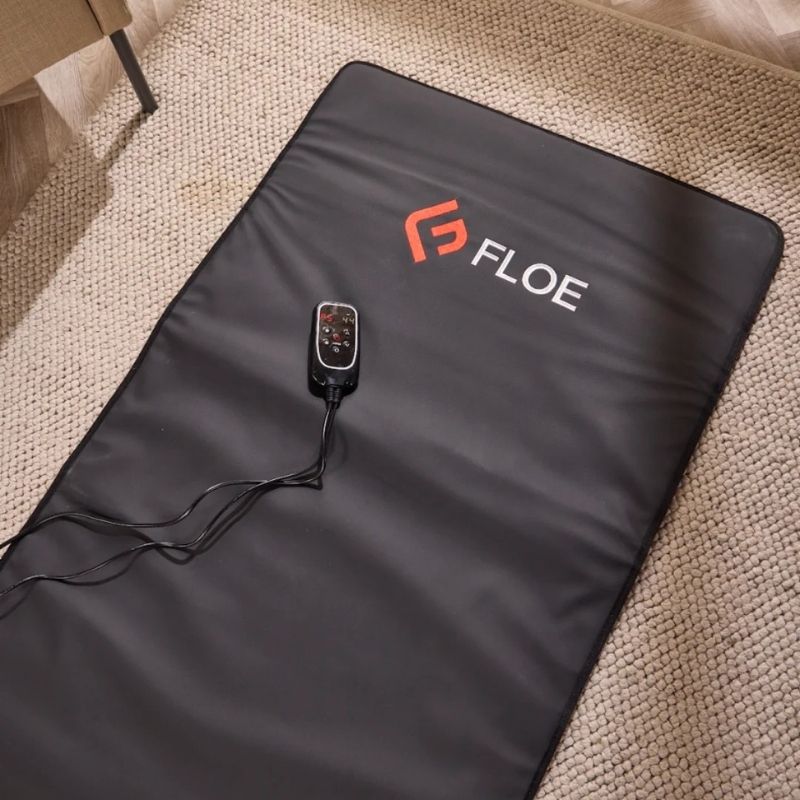 Black heating pad with 'Floe' branding on a textured surface
