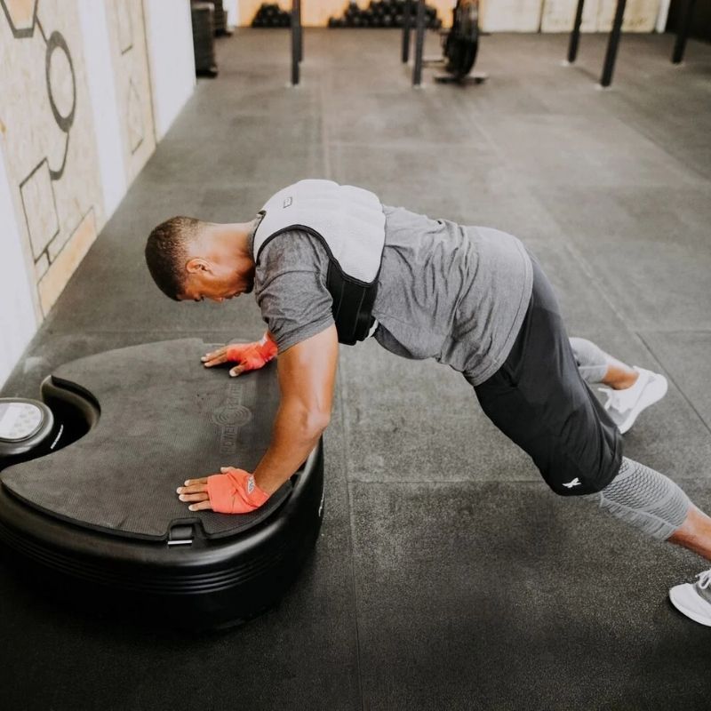 Person doing push-ups on a black mat in a gym setting