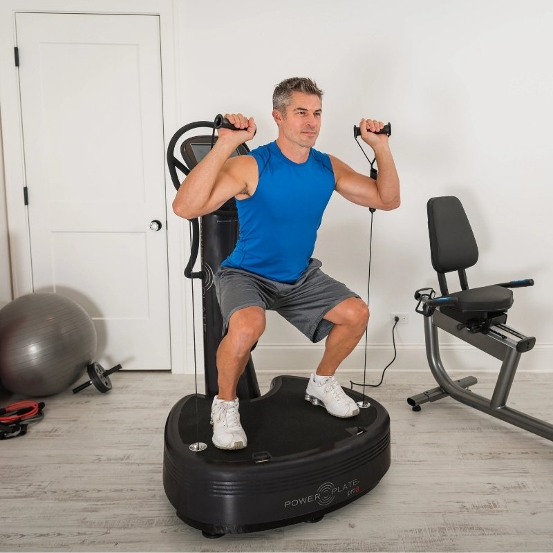 Man exercising on a black exercise machine in a home gym setting.