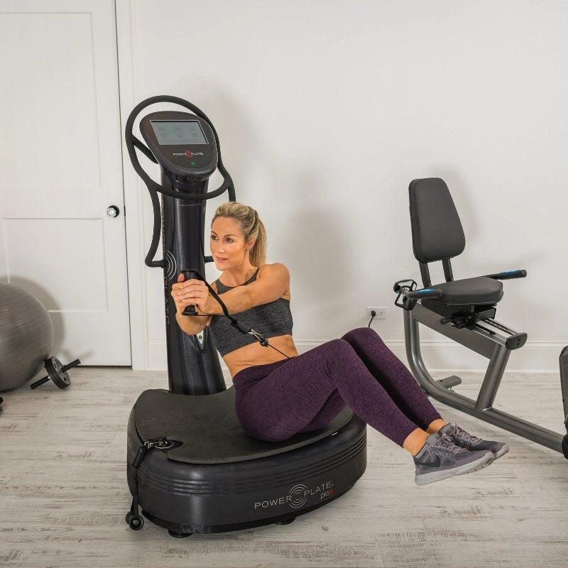 Woman using a Power Plate machine in a home gym setting