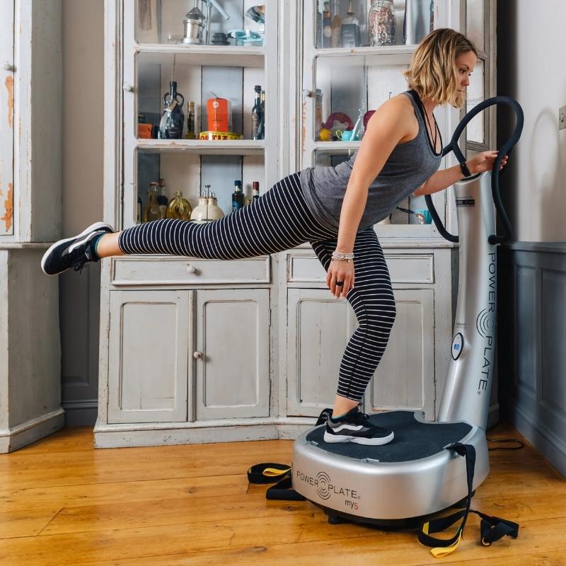Woman using a vibration plate machine in a home setting