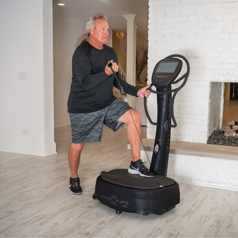 Man using a vibration plate machine in a home setting