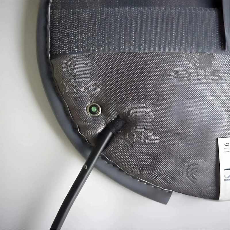 Close-up of a gray bag with a brand logo and a green light on a white background