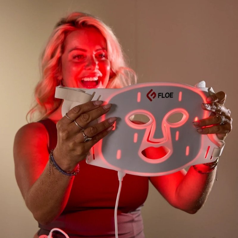Person holding a FLOE red light face mask with red light, brand visible