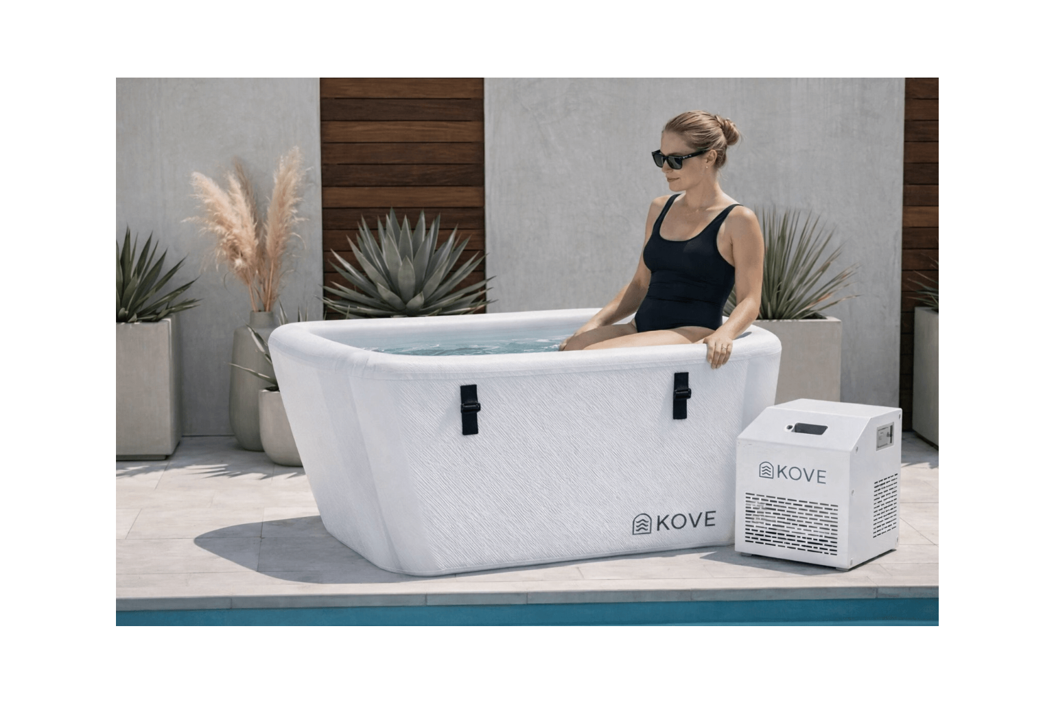 Woman sitting in a portable hot tub with Kove branding outdoors.